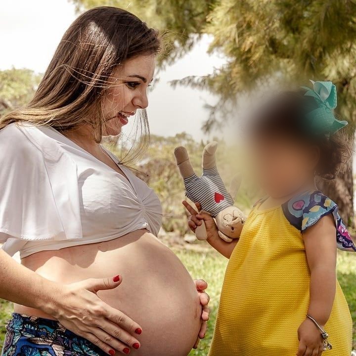 Flávia Maitri grávida ao lado de uma criança, símbolo de maternidade e infância